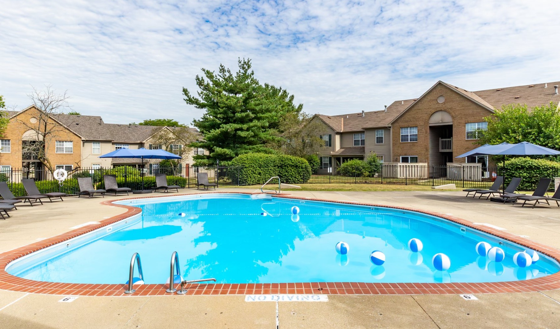 Apartment pool in Riverside swimming pool with chairs, umbrellas, and beach balls